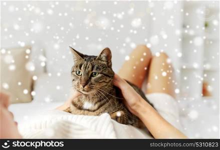 pets, comfort, winter and people concept - young woman with cat lying in bed at home over snow. young woman with cat lying in bed at home