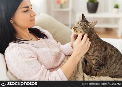 pets, hygge and people concept - close up of woman with tabby cat in bed at home. close up of woman with tabby cat in bed at home
