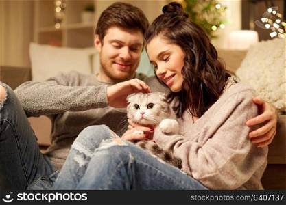 pets, hygge and people concept - happy couple with cat at home. happy couple with cat at home