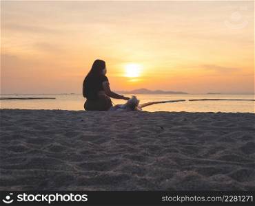 Pets love concept from silhouette of woman and dog sitting together on the beach at sunset