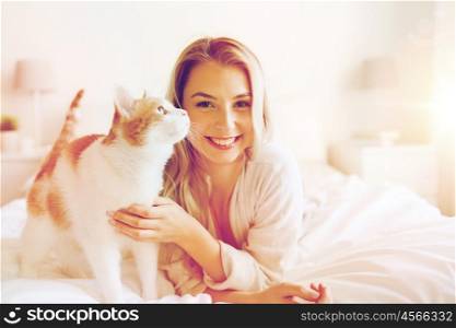pets, morning, comfort, rest and people concept - happy young woman with cat in bed at home