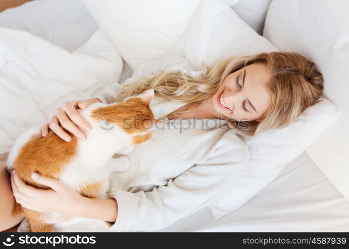 pets, morning, comfort, rest and people concept - happy young woman with cat in bed at home