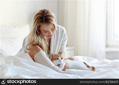 pets, morning, comfort, rest and people concept - happy young woman with cat in bed at home