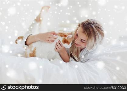 pets, morning, comfort, rest and people concept - happy young woman with cat in bed at home over snow. happy young woman with cat in bed at home