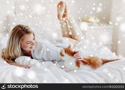 pets, morning, comfort, rest and people concept - happy young woman with cat in bed at home over snow. happy young woman with cat in bed at home