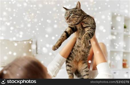 pets, winter and people concept - young woman with cat lying in bed at home over snow. young woman with cat lying in bed at home