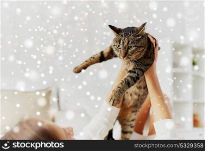 pets, winter and people concept - young woman with cat lying in bed at home over snow. young woman with cat lying in bed at home