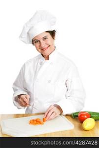Petty female chef in her uniform, cutting up a variety of fresh organic vegetables on her cutting board in the kitchen. Isolated on white background.