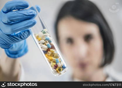 Pharmaceutical research. Doctor s hand holding laboratory glass test tube filled with colorful pills. . Pharmaceuticals. Glass Test Tube Filled With Colorful Pills