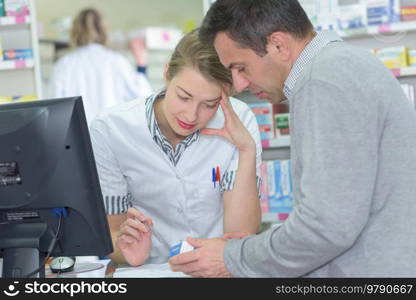 Pharmacist looking at prescription with male customer