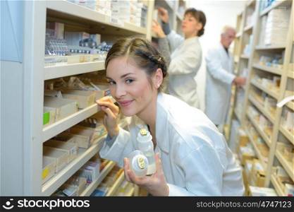Pharmacist selecting medication from shelves