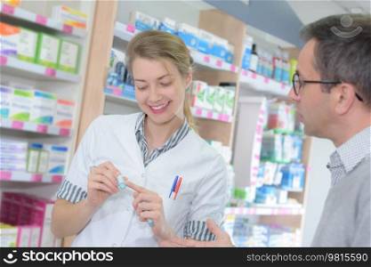 Pharmacist showing label to customer