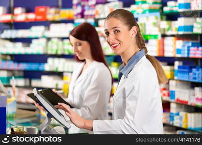 Pharmacist with female assistant in pharmacy standing at the cashpoint