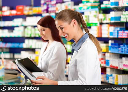 Pharmacist with female assistant in pharmacy standing at the cashpoint