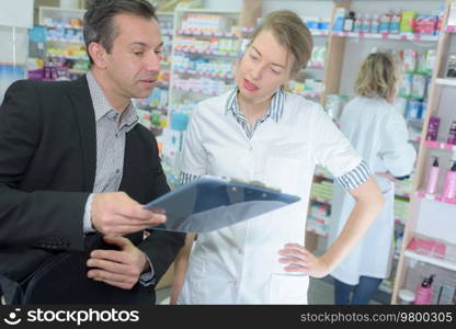 pharmacists discussing on clipboard in pharmacy