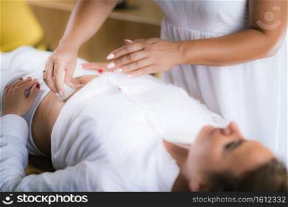 Philippine Psychic Surgery Healer Working with Female Patient, Placing Wet Cotton Ball on her Stomach.. Spiritual Healer Using Cotton Balls and Water for Philippine Psychic Surgery Treatment
