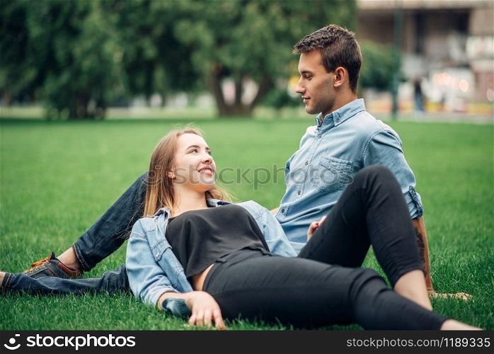 Phone addicted people, man and woman lies on the grass in summer park and using their smartphones, social addict