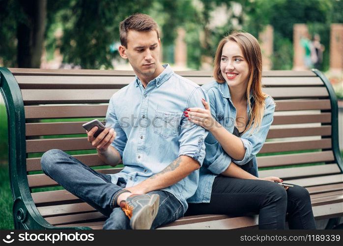 Phone addicted people, man using smartphone and ignoring his woman, couple in summer park, social addict