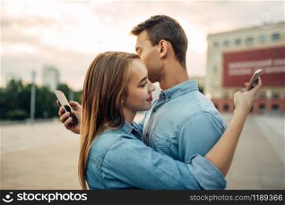 Phone addiction, addict couple hugs and using gadgets, social addicted people, modern relationship