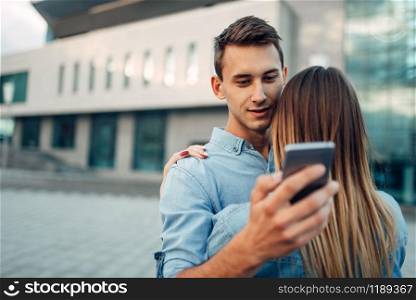 Phone addiction, addict man hugs his woman and using gadget at this time, social addicted people, modern relationship