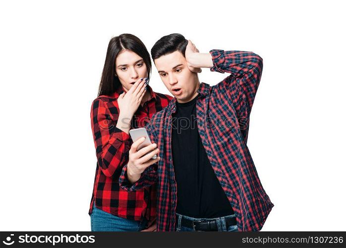 Phone addiction, surprised couple looks on smartphone screen, white background. Consciousness manipulation concept