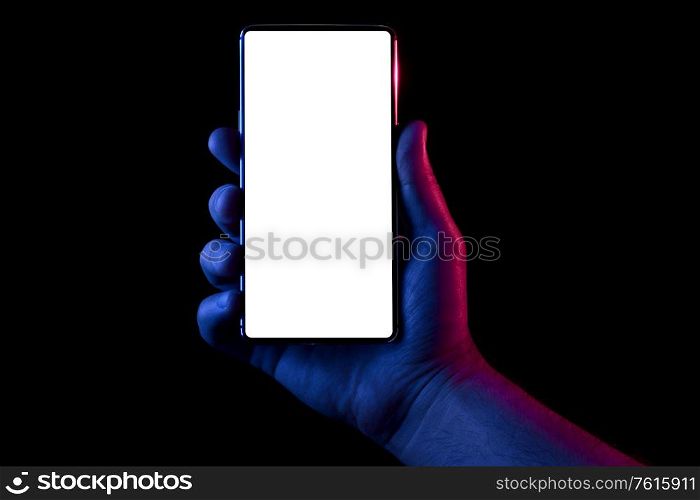 Phone in hand. Silhouette of male hand lit with blue and red neon lights holding bezel-less smartphone on black background. Screen is cut with clipping path.. Phone in hand