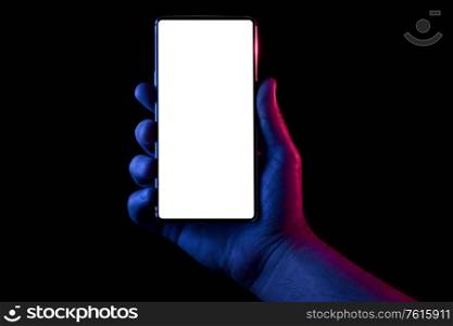 Phone in hand. Silhouette of male hand lit with blue and red neon lights holding bezel-less smartphone on black background. Screen is cut with clipping path.. Phone in hand