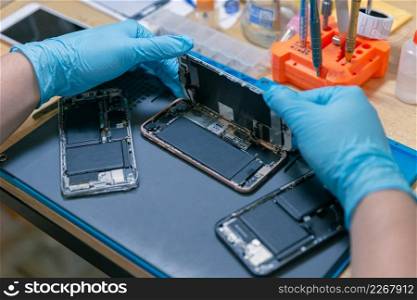 Phone repair concept a mobile phone being assembled by the repairman on the desk with the various specific equipment.