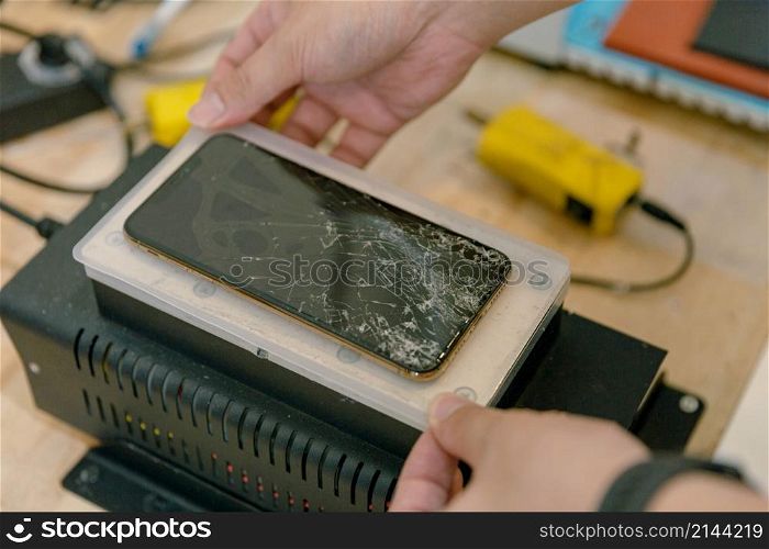 Phone repair concept a smartphone with broken screen being repaired with the specific tools by the professional technician.
