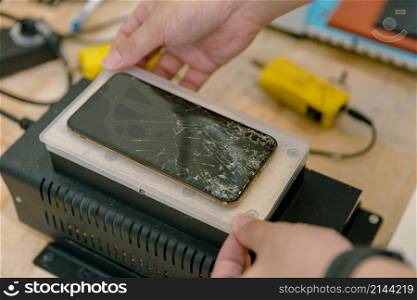 Phone repair concept a smartphone with broken screen being repaired with the specific tools by the professional technician.