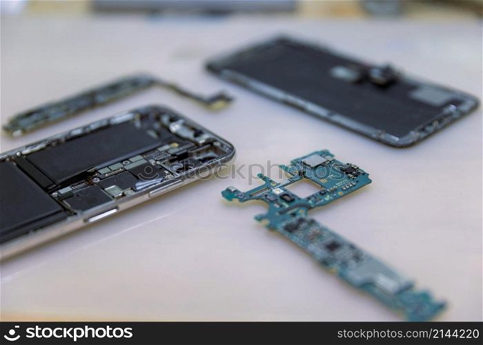 Phone repair concept several electronic devices taken apart into the components like the covers, circuit boards, bodies.