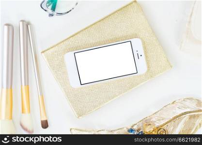 Phone with golden woman accessories mock up flat lay styled scene, top view, copy space on empty screen background. Offise desktop scene