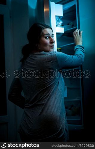 Photo at night of woman opening refrigerator