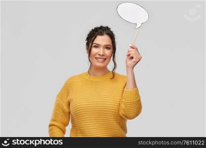 photo booth, communication and people concept - portrait of happy smiling young woman with pierced nose holding blank speech bubble party accessory over grey background. smiling young woman holding speech bubble