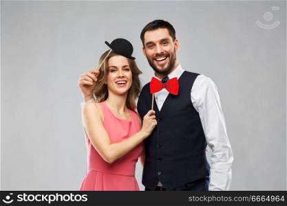photo booth, fun and people concept - happy couple posing with party props over grey background. couple with party props having fun and posing