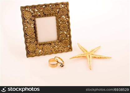 Photo frame, starfish and rings placed on a white background