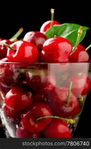 photo glass with cocktail cherries in front of black isolated background
