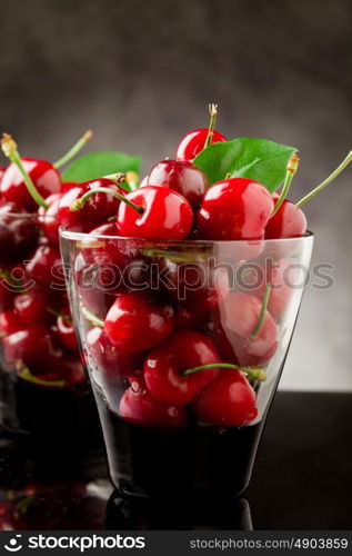 photo glass with cocktail cherries with green leaves