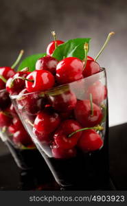 photo glass with cocktail cherries with green leaves