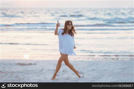 Photo in motion of a happy woman dancing on the beach. Having fun outdoors. Spending active summer holidays near the sea. Blur in motion. Photo in motion of a dancing woman