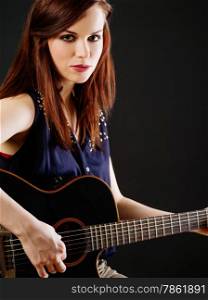 Photo of a beautiful brunette female playing an acoustic guitar over black background.