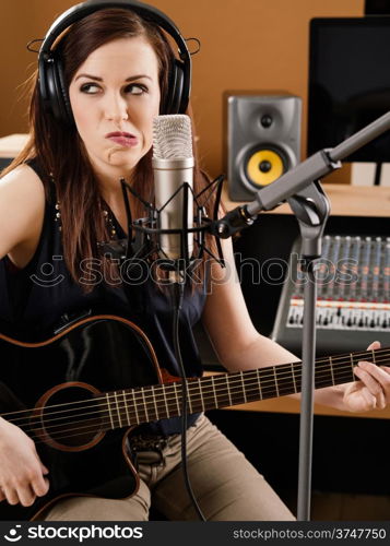 Photo of a beautiful brunette in a recording studio uncertain about the quality of her playing.
