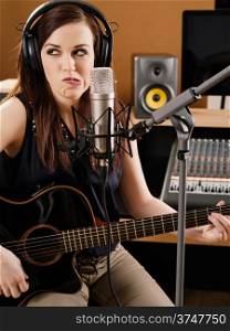 Photo of a beautiful brunette in a recording studio uncertain about the quality of her playing.