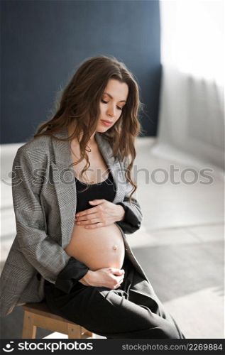 Photo of a beautiful pregnant woman with a bare stomach.. A pregnant girl with a bare stomach is sitting on a stepladder 4126.