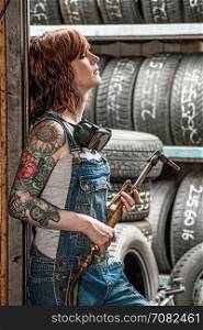 Photo of a beautiful redhead female mechanic with tattoos holding a welding torch.