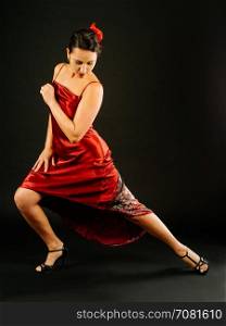 Photo of a beautiful woman dancing the tango over dark background.