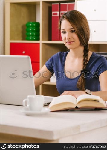 Photo of a beautiful woman using a laptop, drinking coffee, and reading a book.&#xA;