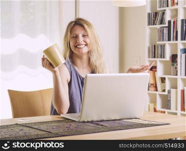 Photo of a beautiful young female shopping online and drinking coffee.