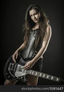 Photo of a beautiful young sexy woman holding an electric guitar over black background.