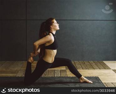 Photo of a beautiful young woman doing a kneeling quad stretch.. Redhead woman doing kneeling quad stretch